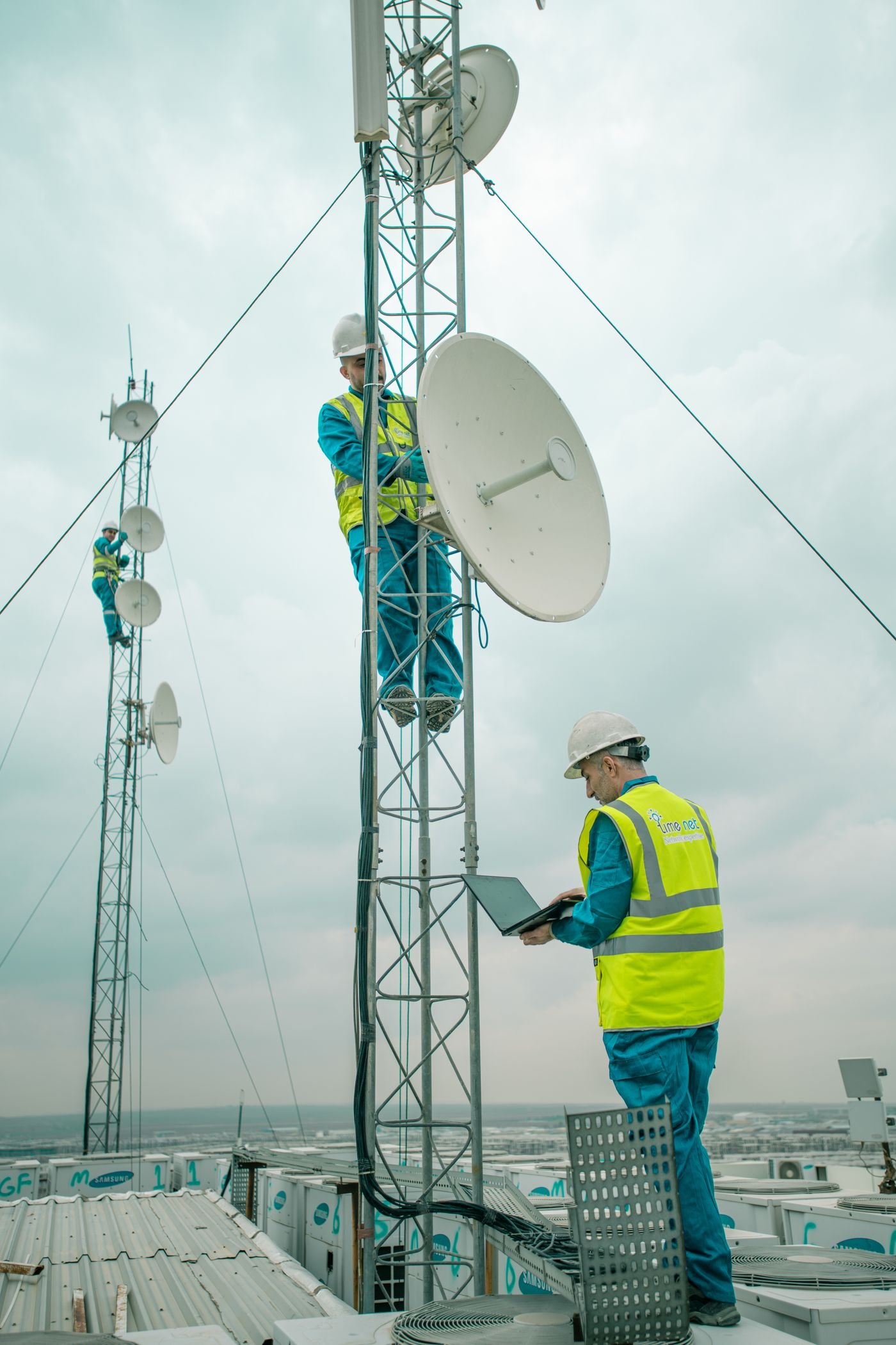 Techniciens installant des antennes de transmission sur un pylône